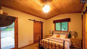 A bedroom with a wooden ceiling, a bed with a headboard, a window, and a door. - Murphy Mountain House - Creeks, Firepits & High Speed Internet! (Murphy)