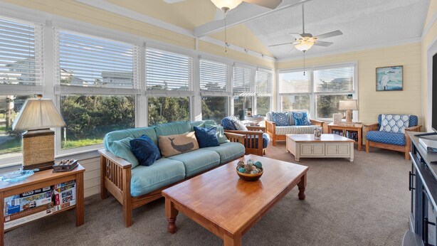 A sunroom with a large window, a ceiling fan, and a wooden coffee table. - 7589- Anchored in the Sand - Avon Beach Cottage | 60 Yards to Beach (Avon)