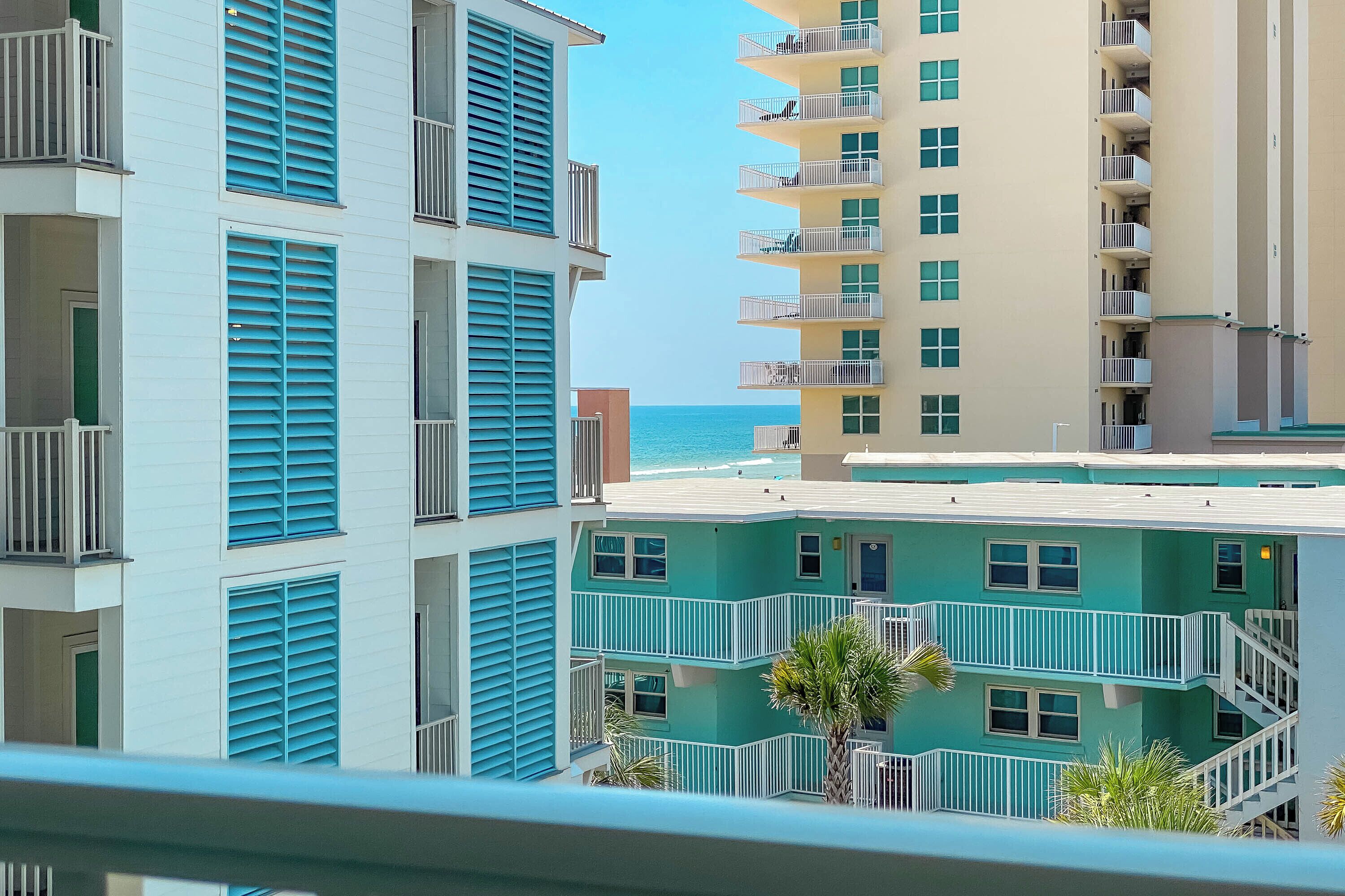A multi-story hotel with balconies and a view of the ocean.