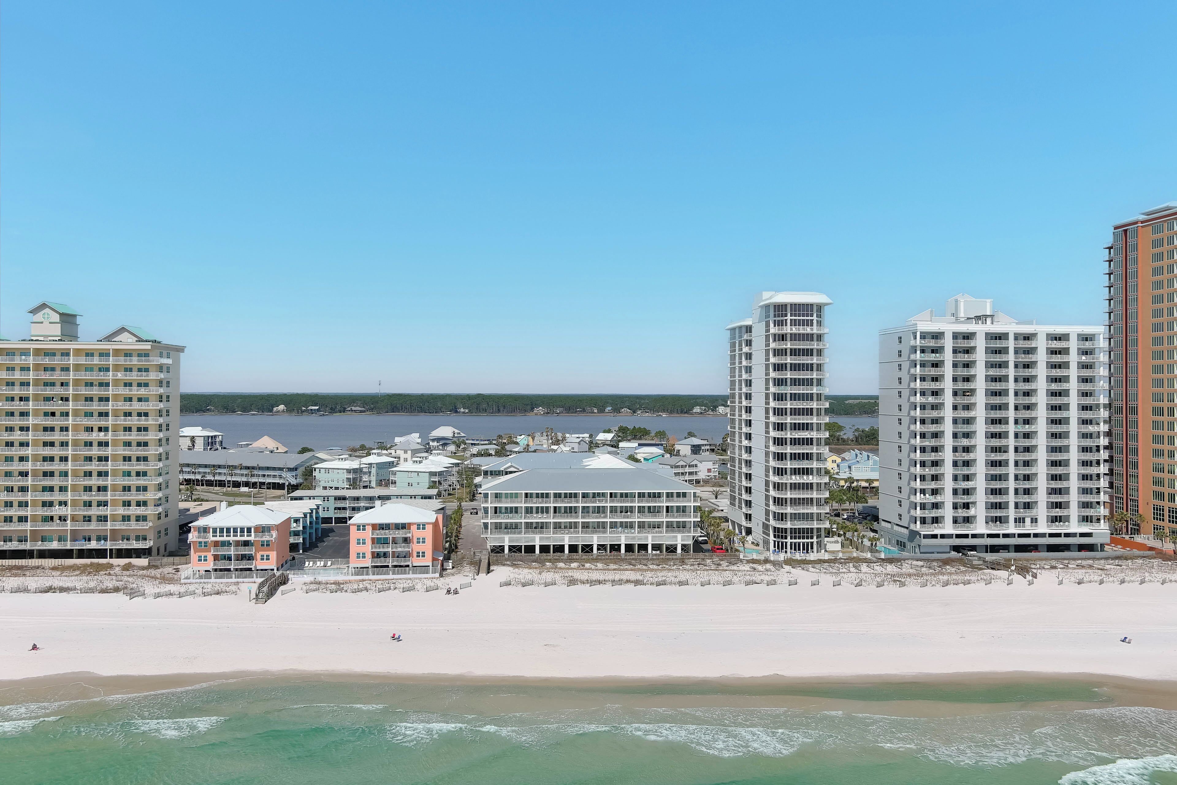 Un paisaje urbano costero con rascacielos, una playa y un puerto deportivo.