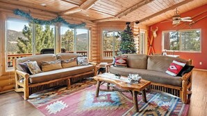 A log cabin interior with a wooden ceiling, two sofas, a coffee table, and a Christmas tree. - The Moose Lodge. Stunning Mtn Views. Spa. Games. (Big Bear Lake)