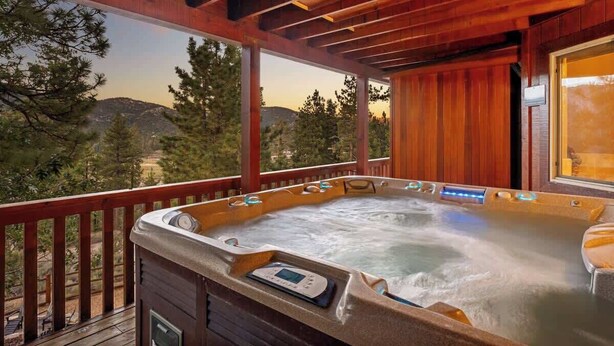 A hot tub on a wooden deck with a view of trees and hills. - The Moose Lodge. Stunning Mtn Views. Spa. Games. (Big Bear Lake)