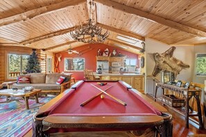 L’intérieur d’un chalet confortable, avec une table de billard, des meubles en bois et une décoration rustique.