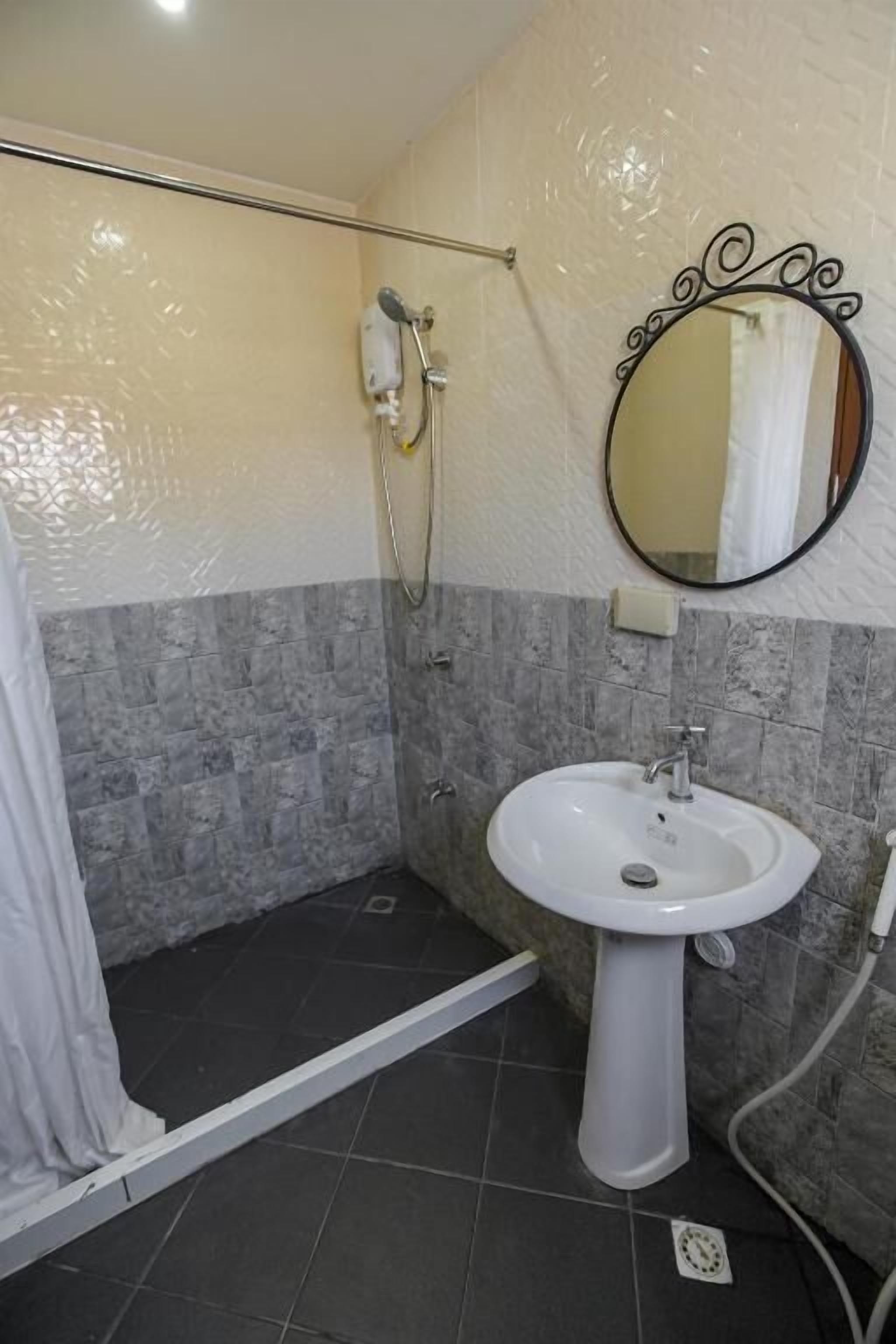 Un baño con ducha, lavamanos y espejo.