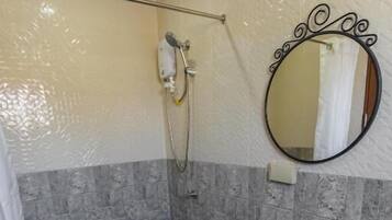 Un baño con ducha, lavamanos y espejo.