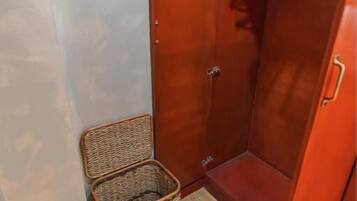 A wooden closet with a hanging rod and a wicker basket.