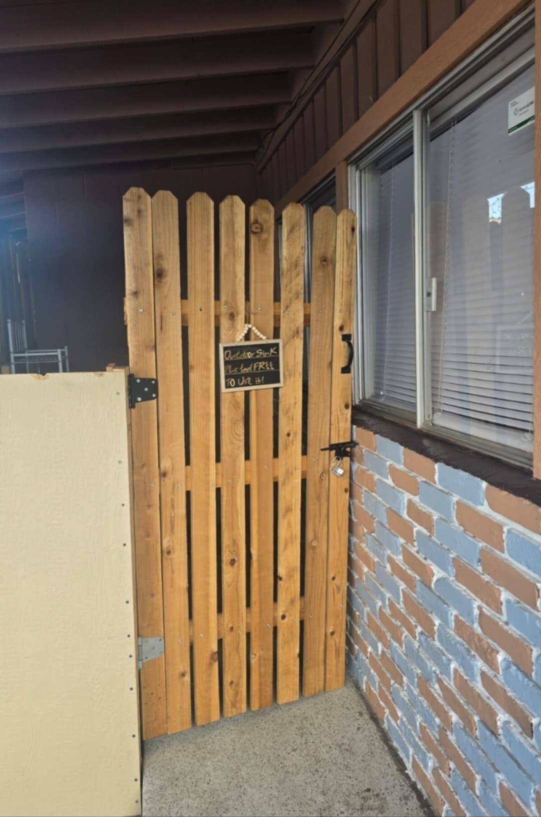 Een houten poort met een bord waarop staat: 'Buiten, geurvrij, gebruik het!'