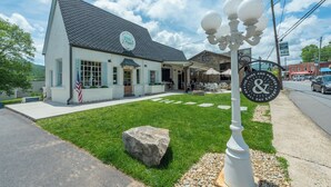 A white building with a black roof, a sign reading "PURE & Prager," and a street lamp with a sign that says "The Pure & Prager All Day Eatery." - Cherry Street Loft (A) | In the Heart of Downtown Black Mtn! (Black Mountain)