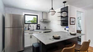 A modern kitchen with a stainless steel refrigerator, a built-in oven, a coffee maker, and a large island with seating. - Cherry Street Loft (A) | In the Heart of Downtown Black Mtn! (Black Mountain)