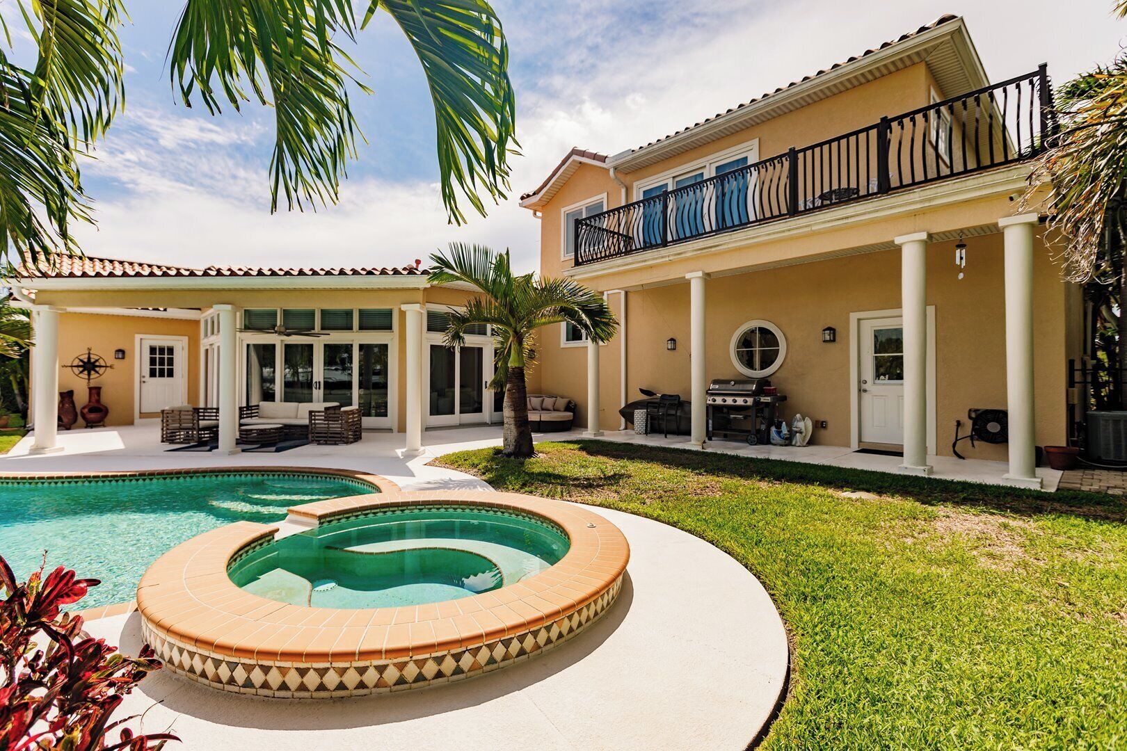 Una casa de dos pisos con piscina, un patio cubierto y zona de barbacoa.