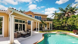 A house with a swimming pool, outdoor furniture, and a covered patio area. - New Listing! Luxury 4BR Canal Home with Pool. Monthly Rental.    (Holmes Beach)