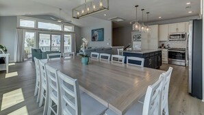 Een moderne keuken met een groot eiland, witte kasten en roestvrijstalen apparatuur.