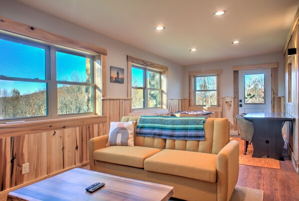 A cozy living room with a sofa, a coffee table, and a desk area.