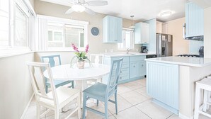 Una cocina con armarios azul claro, una isla blanca y un ventilador de techo.