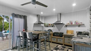 Een moderne keuken met een centraal eiland, barstoelen, een gasfornuis en een plafondventilator.