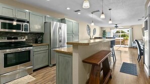 Een moderne keuken met roestvrijstalen apparatuur, lichte kasten en een centraal eiland.
