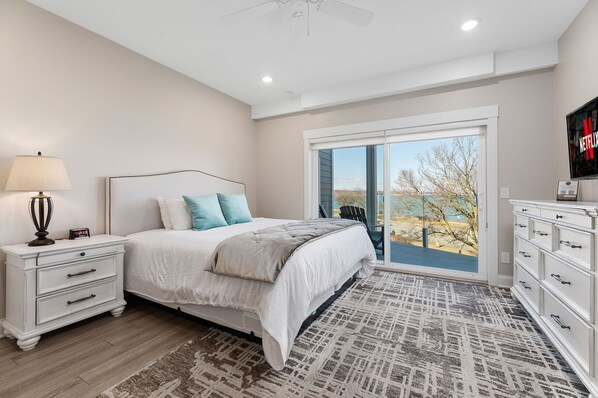 Relax in this serene bedroom with a large bed, nightstand, and sliding glass door leading to a scenic outdoor area.