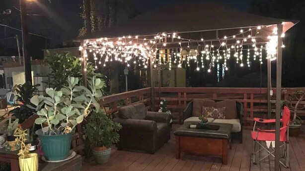 Une terrasse extérieure avec un plancher en bois, des plantes en pot et du mobilier d’extérieur.