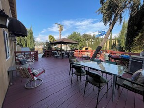 An outdoor patio with a glass table, chairs, and a covered seating area.