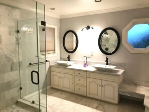 A bathroom with two sinks, a glass shower enclosure, and a large mirror.