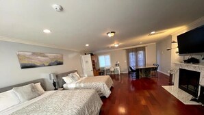Une chambre d’hôtel avec deux lits, une télévision, une cheminée et un coin repas comprenant une table et des chaises.