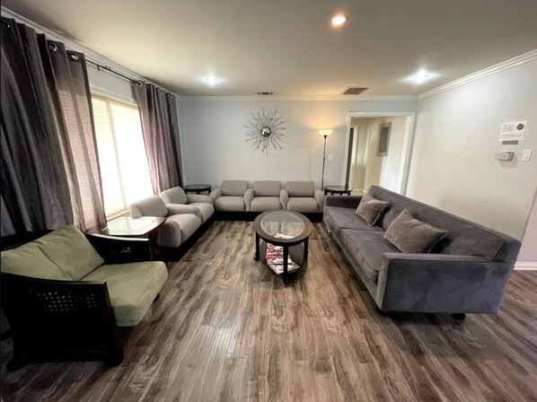 A living room with a sectional sofa, a single armchair, a coffee table, and a floor lamp.
