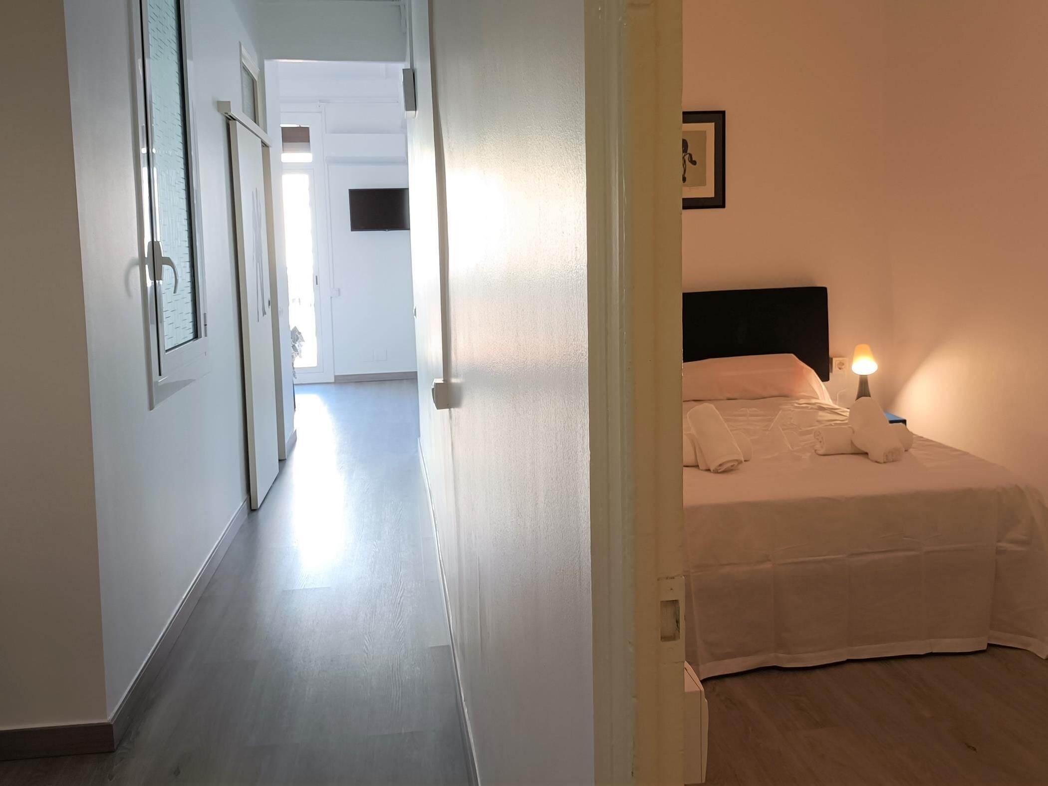 Habitació d'hotel amb un llit, una tauleta de nit i una televisió penjada a la paret.