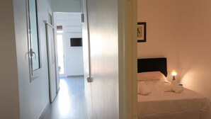 Une chambre d’hôtel avec un lit, une table de chevet et un téléviseur fixé au mur.