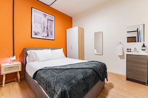 Relax in a spacious room with a large bed, bedside table, and wardrobe, plus a convenient vanity with sink and toiletries.