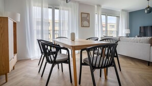 Una sala de estar moderna con comedor, ventanas amplias y vista a la ciudad.