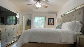 A bedroom with a bed, a ceiling fan, a dresser, a television, and a window. - Pacifico Blu Guest House- close to beaches! (Clearwater)