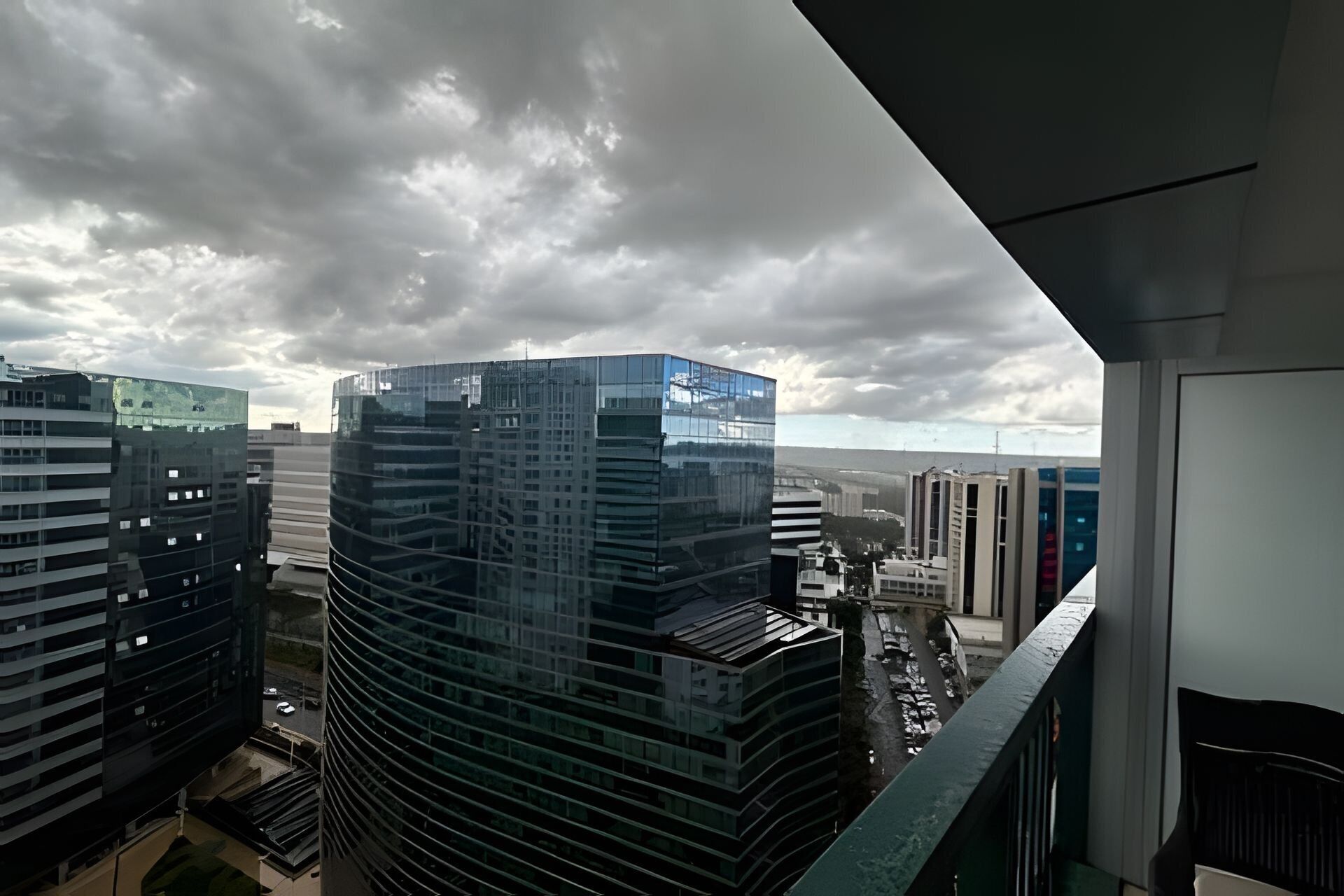 A high-rise building with a curved glass facade, surrounded by other modern buildings.
