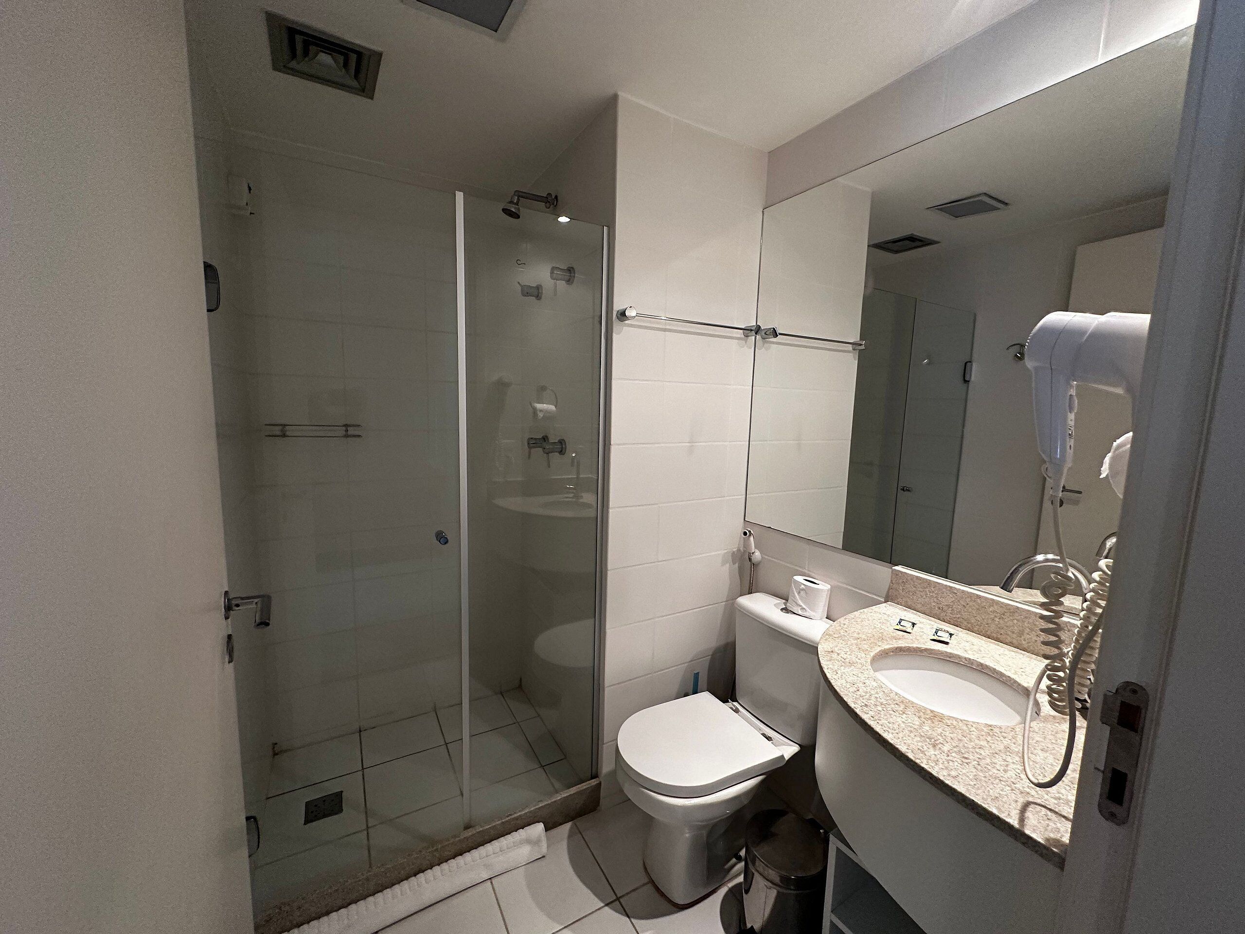 Une salle de bain avec une douche à parois de verre, des toilettes et un lavabo avec un miroir au-dessus.