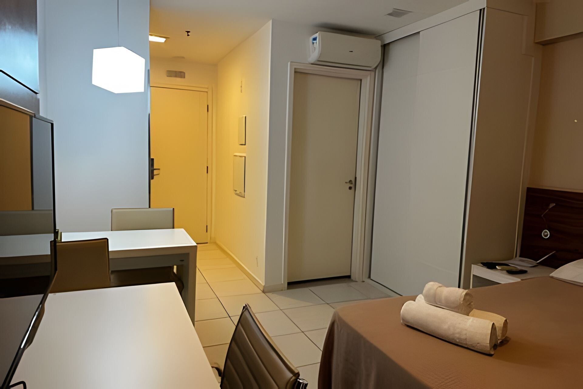 Une chambre d’hôtel équipée d’un lit, d’un bureau, d’une chaise, d’une armoire et d’un appareil de climatisation.