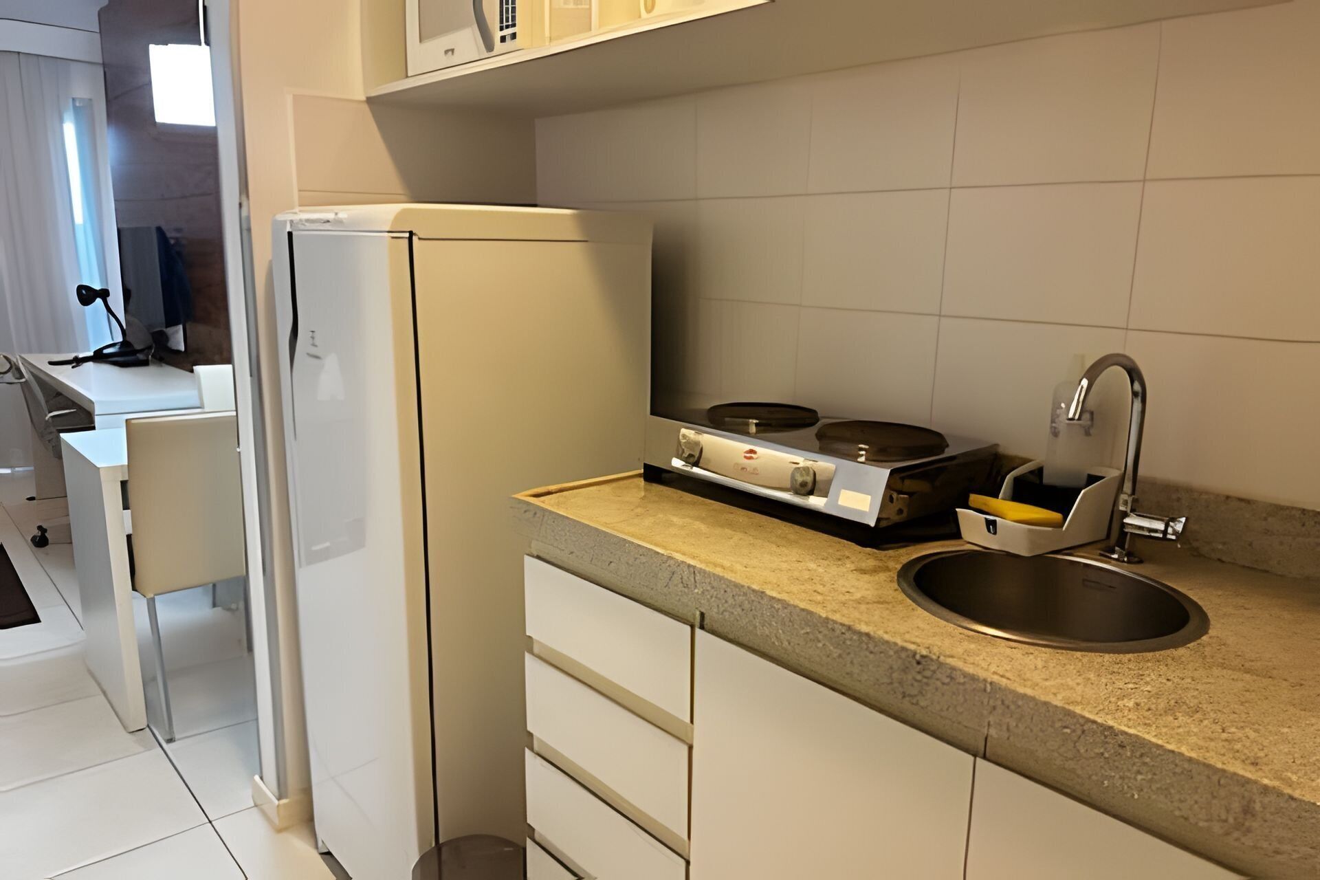 Une cuisine de taille réduite équipée d’un réfrigérateur, d’une cuisinière et d’un évier.