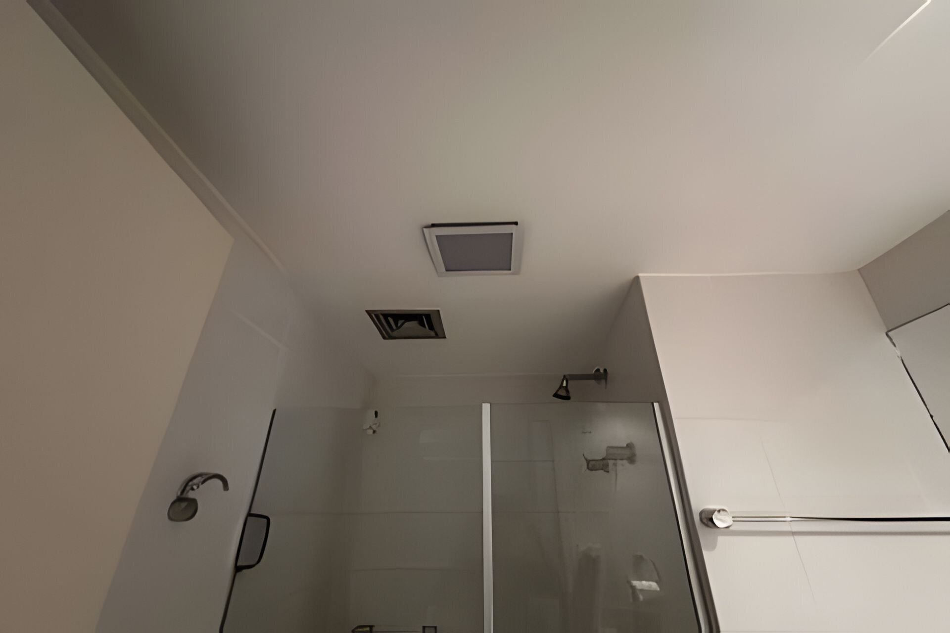 A bathroom with a glass shower enclosure, a white ceiling, and a visible light fixture.