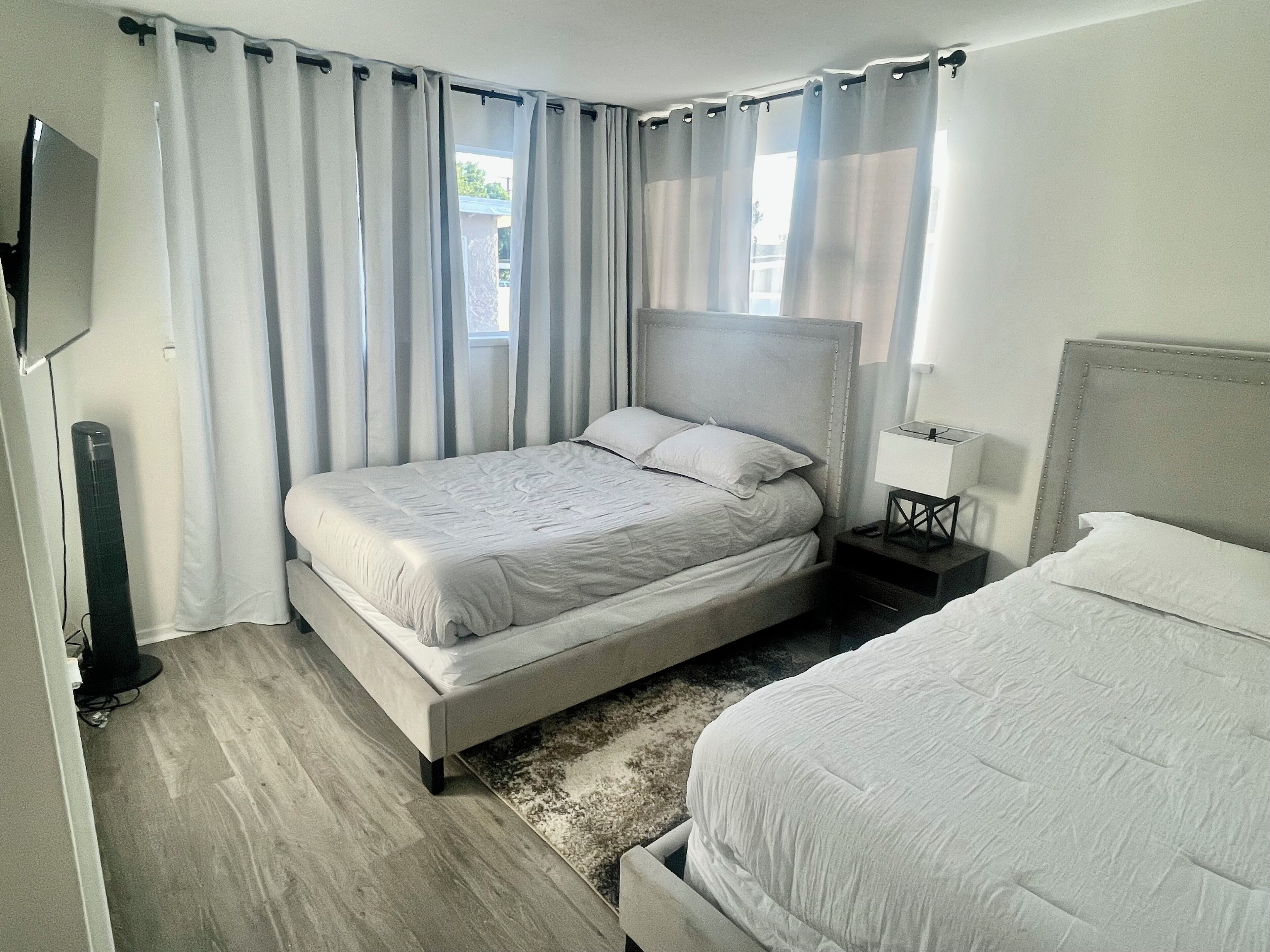 A modern hotel room with a large bed, a bedside table, a lamp, and a flat-screen TV.