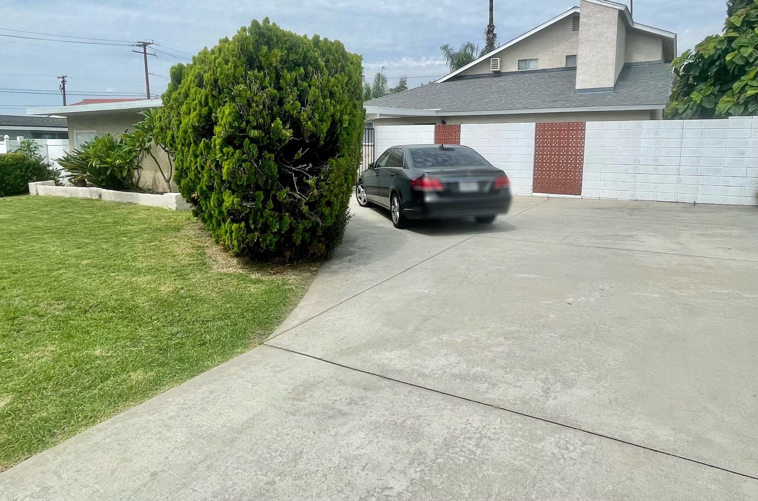 A residential driveway with a parked car and a well-maintained lawn.