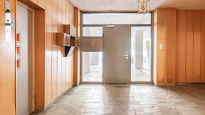 A hallway with wooden paneling, a glass door, and a stone-tiled floor. - Serenity & Luxury - Elegant 2BR in Kifisia's Center (Kifisia)