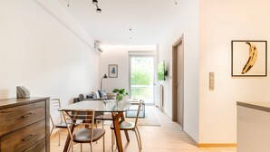 A modern dining area with a glass table, wooden chairs, and a wooden cabinet. - Serenity & Luxury - Elegant 2BR in Kifisia's Center (Kifisia)