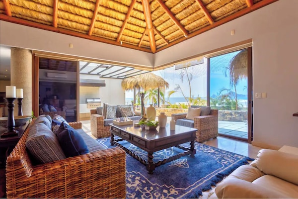 The living room with a view of the pool and the ocean
