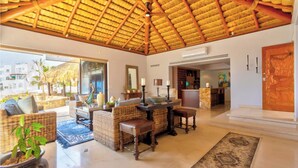 A spacious lobby with wicker furniture, a reception desk, and a view of the outside. - Infiniti Pool-View of Arch, Oceanview-Walk to Beach, Cape Hotel, Close to Dwntn  (Cabo San Lucas)