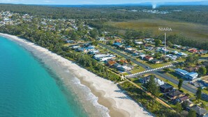 Vista aérea de una zona residencial costera con casas, una playa y cielo despejado.