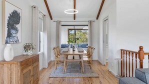 Un comedor con una mesa de madera, sillas y una alfombra. Se observa un aparador de madera y un cuadro en la pared.