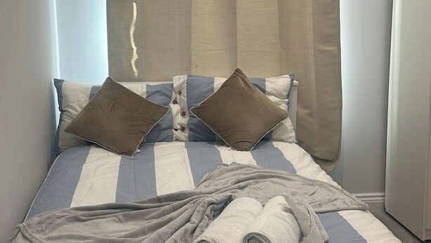 Ein Bett mit gestreifter Bettwäsche, zwei Kissen und einer Decke.