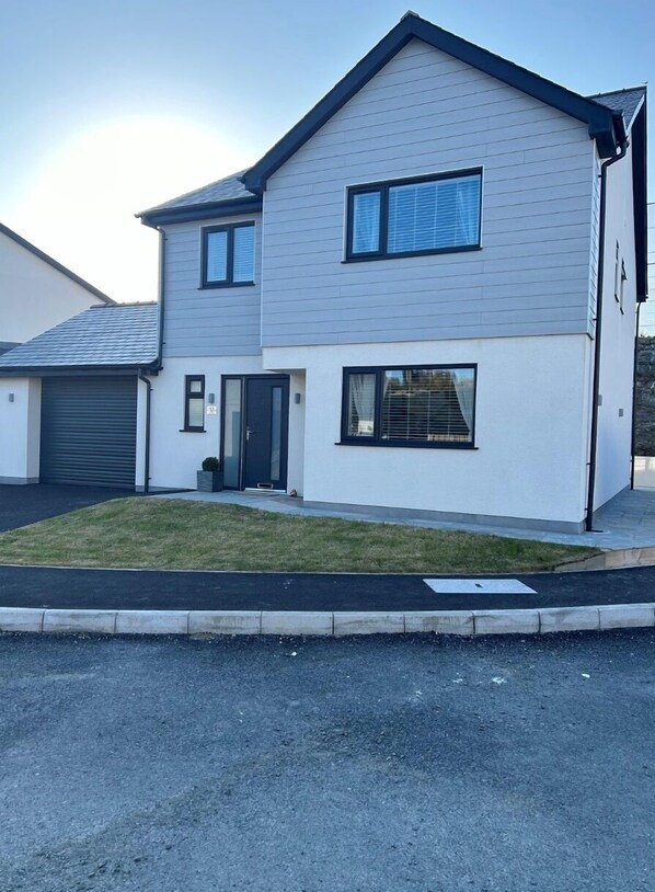 Stylish two-story home with a flat roof, glass door entrance, and a well-manicured lawn.