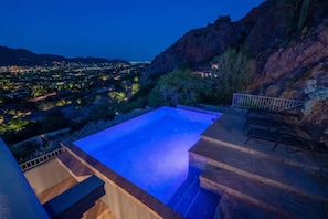 Ein Rooftop-Infinity-Pool mit Blick auf eine Stadtlandschaft im Abenddämmerung.