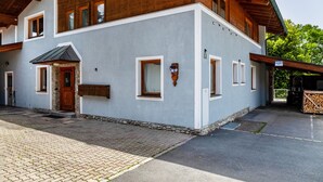 En tvåvåningsbyggnad med en fasad av sten, träbjälkar och ett stenbelagt entréområde.