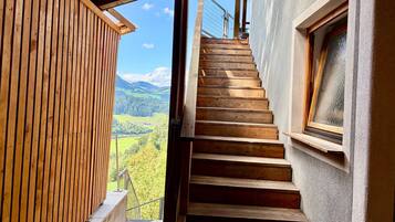 A wooden staircase leading to a balcony with a view of a mountainous landscape.