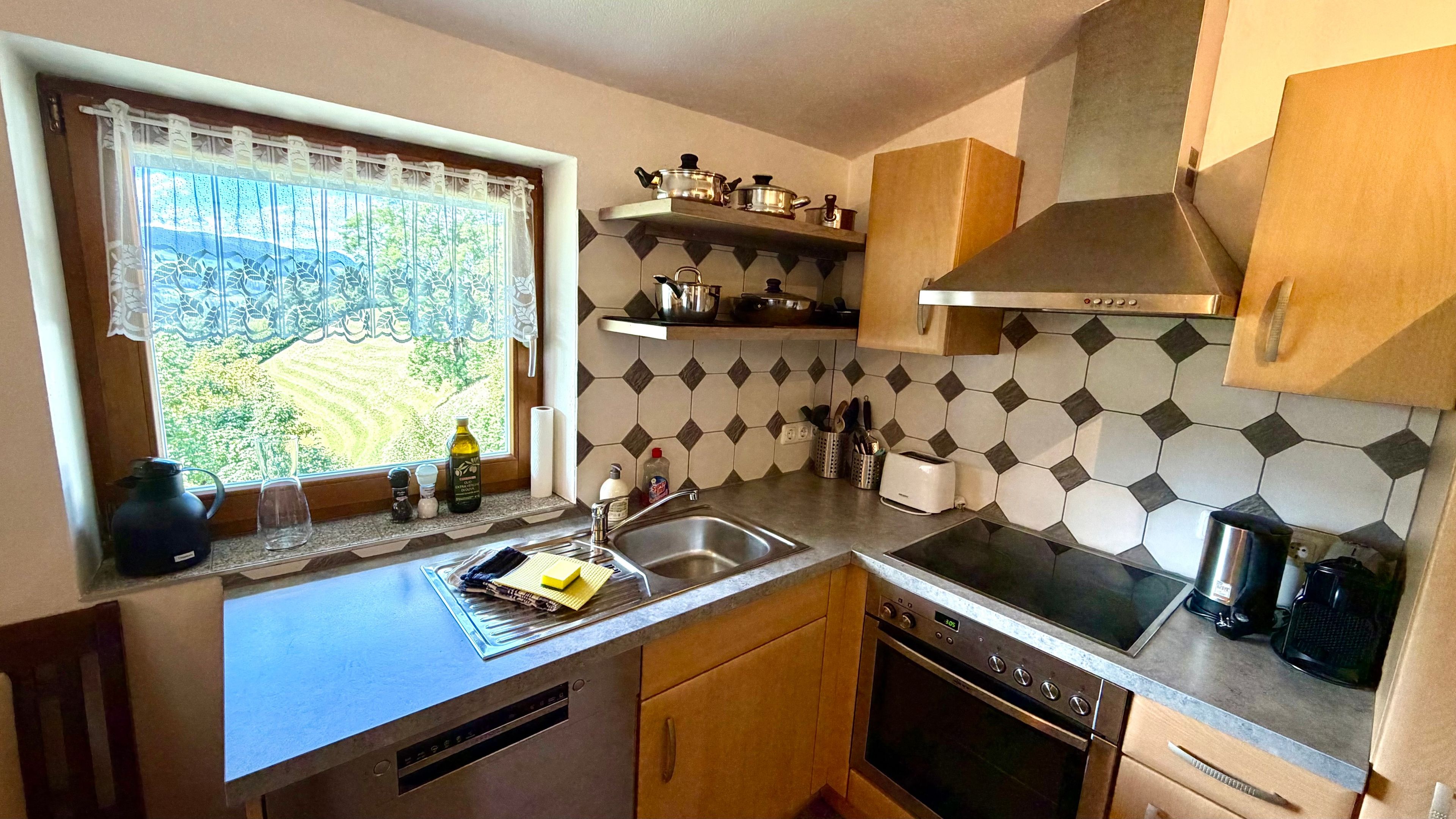 A kitchen with a window, a sink, a stove, and a microwave.